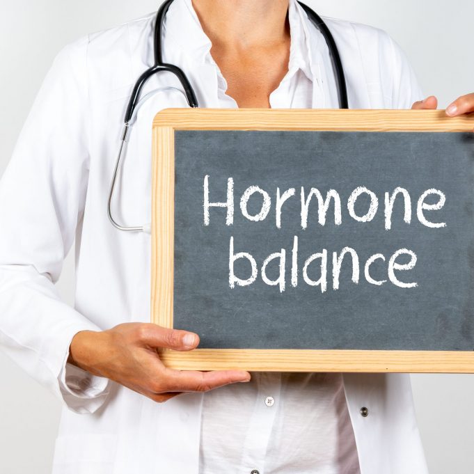 Doctor holding a blackboard with Hormone balance text